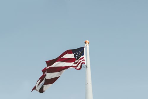 American flag waves in the wind against a light blue sky